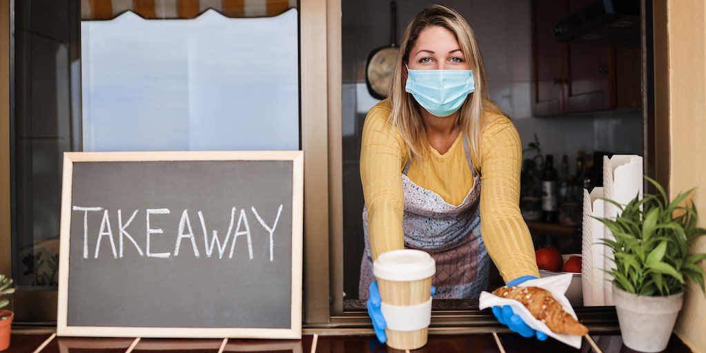 mujer entregando cafe en pandemia con tapabocas